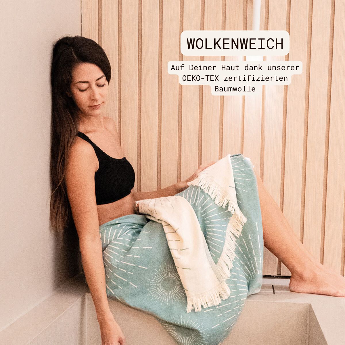 Premium Handtuch / Saunatuch / Strandtuch, Sunshine, in der Größe 95 x 175 cm, in der Farbe Türkis, 100% Baumwolle, Model mit Saunatuch umgewickelt sitzend am Kältebad