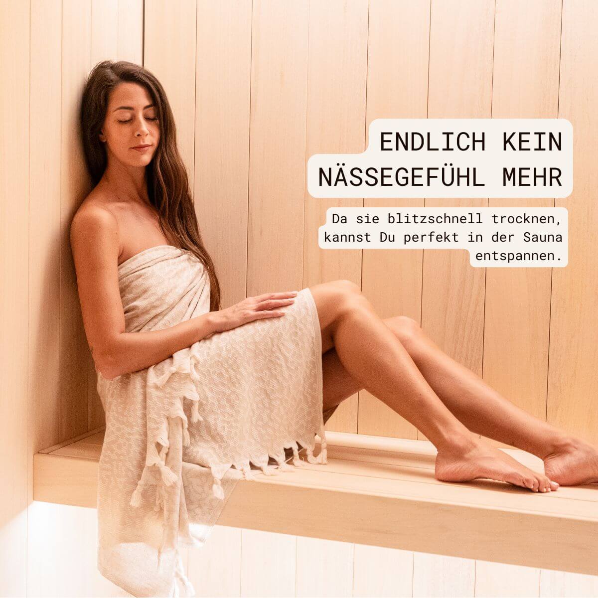 Schnelltrocknendes Saunatuch (95x175 cm) aus 100% OEKO-TEX zertifizierter Baumwolle für Damen | Saunatuch in der Farbe Beige mit Leomuster | Frau sitzt mit umgewickeltem Tuch in der Sauna