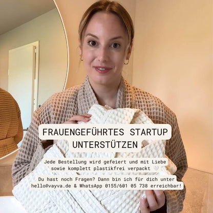 VAYVA Gründerin im Bademantel in Coffee hält einen Bademantel in Natur – frauengeführtes Startup, plastikfrei verpackt
